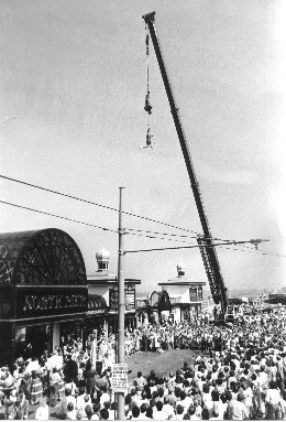 Escapologist Karl Bartoni, escaping from a strait-jacket whilst hanging from a burning rope, with Circus artist Marcia Spence hanging by her hair from him. Blackpool 1986.